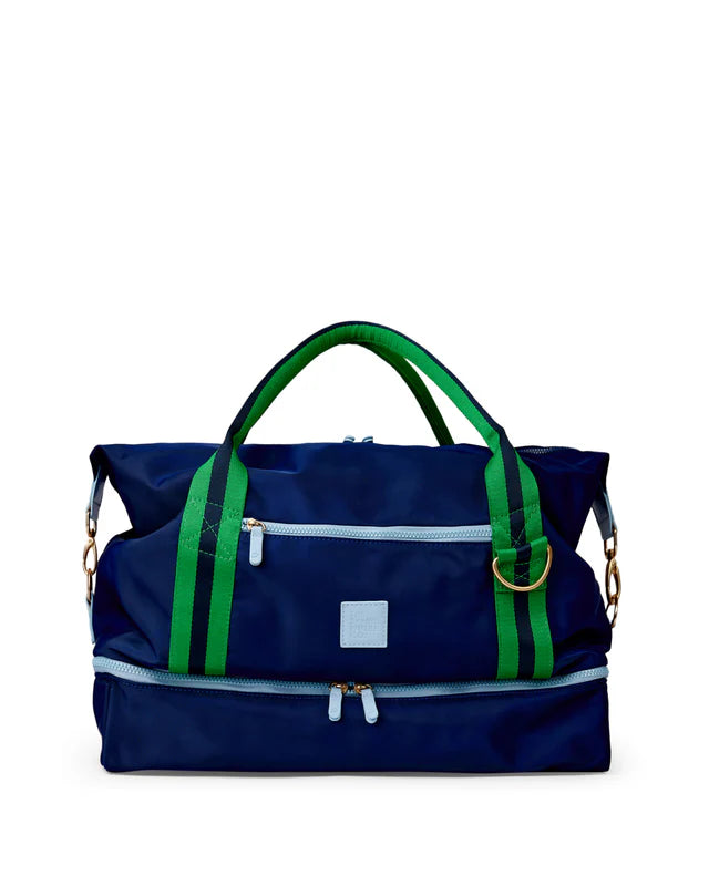 Blue duffel bag with green straps on a white background