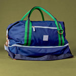 Blue duffel bag with green straps on a green background