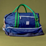 Blue duffel bag with green straps on a green background