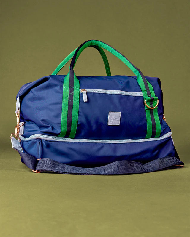 Blue duffel bag with green straps on a green background