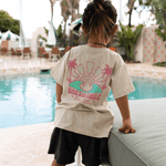 Child wearing a t-shirt with a graphic design by a poolside