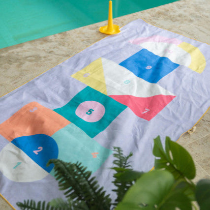 Colorful towel with geometric patterns and numbers on a poolside floor.