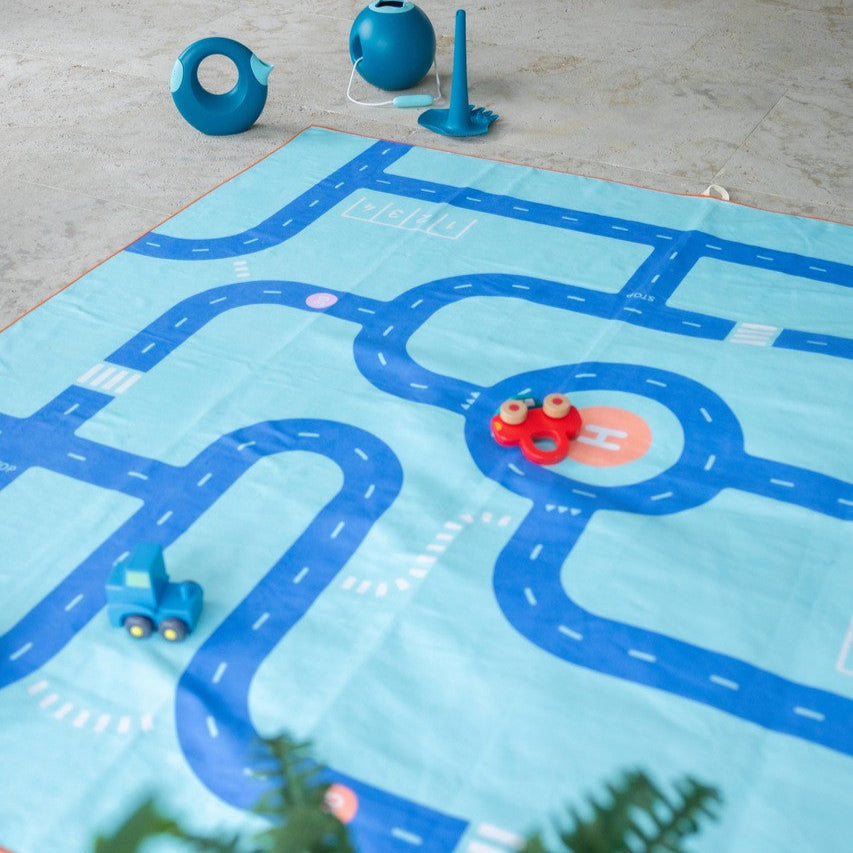 Play mat with road design on a floor with toy cars and traffic lights.
