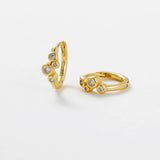 Gold hoop earring and ring with gemstones on a light gray background