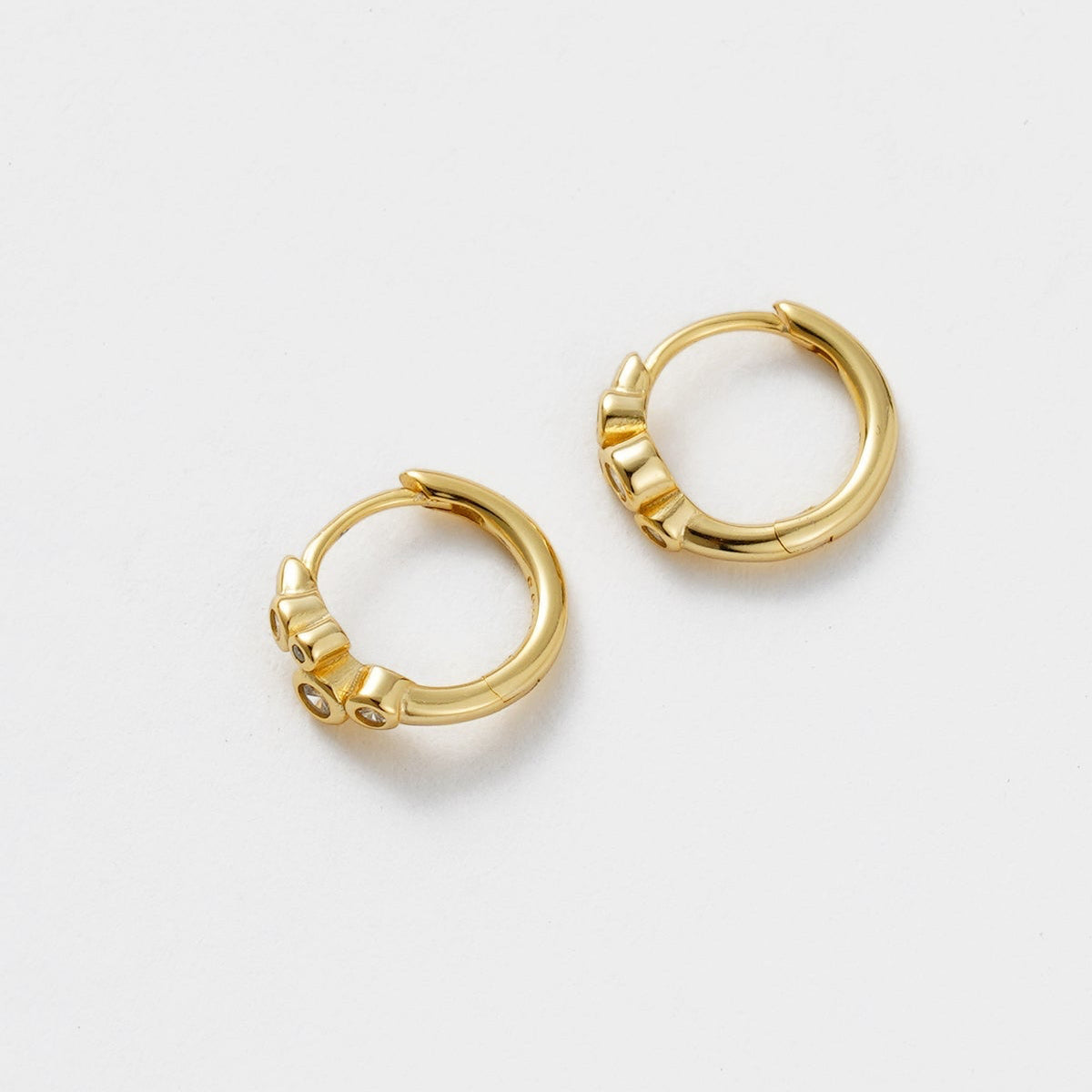 Gold hoop earrings on a light gray background