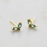 Gold earrings with green gemstones on a light gray background