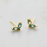 Gold earrings with green gemstones on a light gray background