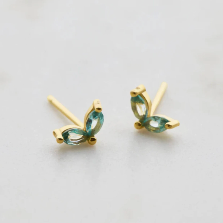 Gold earrings with green gemstones on a light gray background