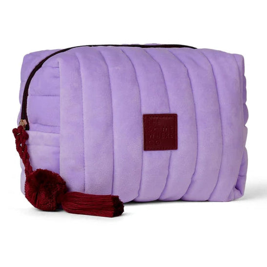 Purple quilted bag with a brown tag and red accents on a white background