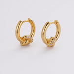 Gold hoop earrings with small diamonds on a light gray background
