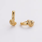 Pair of gold knot earrings on a light gray background