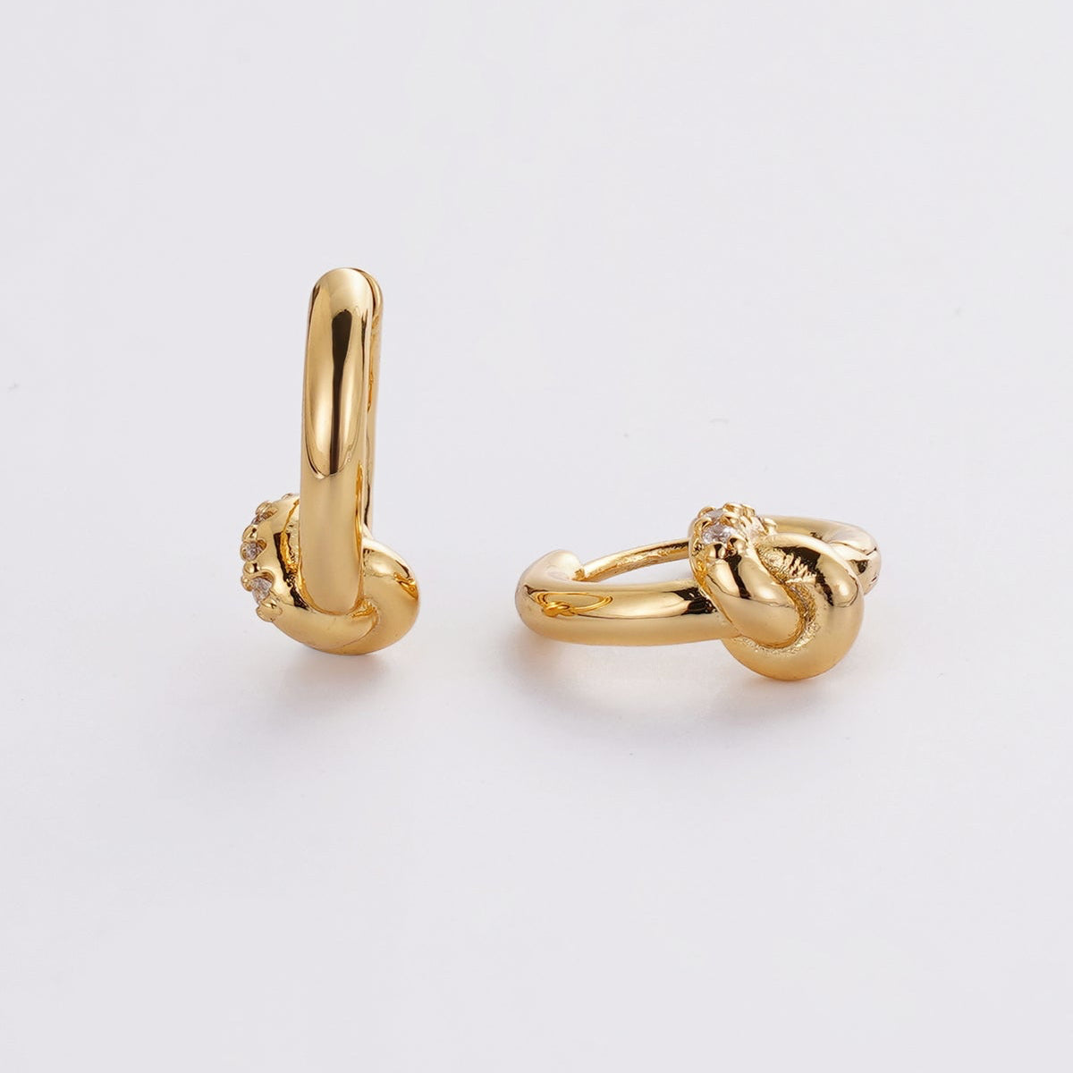 Pair of gold knot earrings on a light gray background