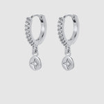 A pair of silver huggie hoop earrings with a curved row of small clear stones and a dangling round star-shaped charm, shown on a light gray background.