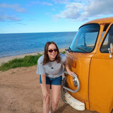 Woman leaning against a yellow van by the ocean