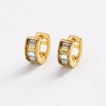Gold hoop earrings with rectangular gemstones on a light gray background