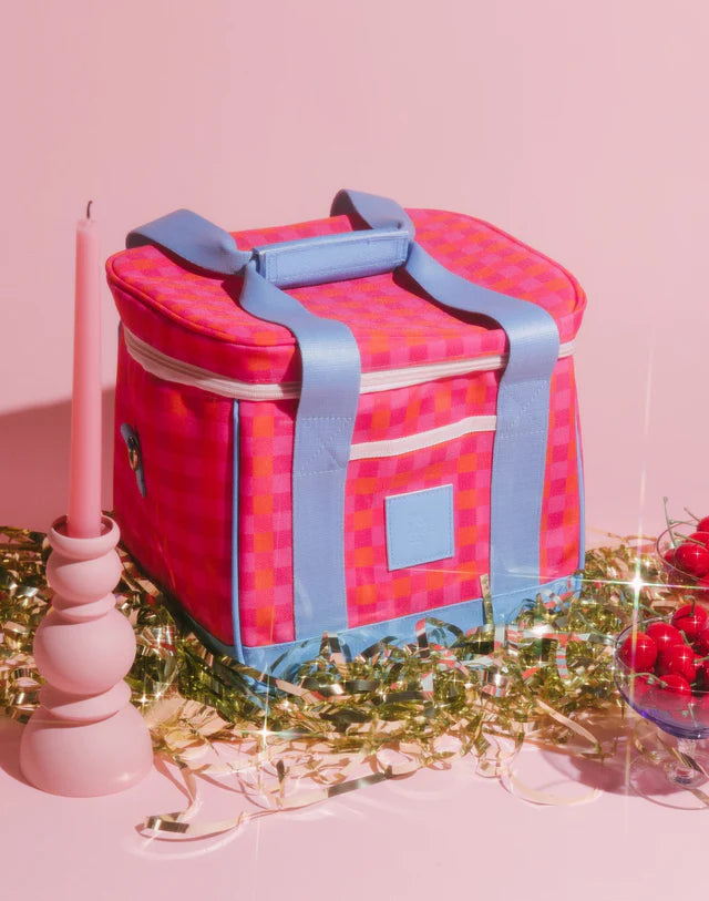 Pink and blue checkered cooler bag on a pink background with decorative elements.