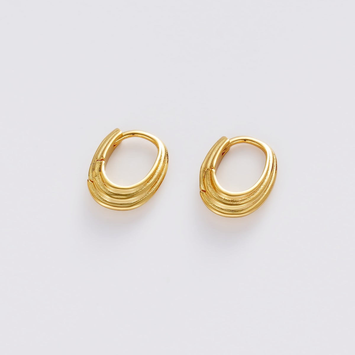 A pair of gold-toned, multi-strand hoop earrings on a clean, light gray background.
