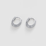 A pair of silver-toned, twisted oval hoop earrings on a light gray background.