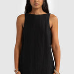 Woman wearing a black sleeveless dress against a white background