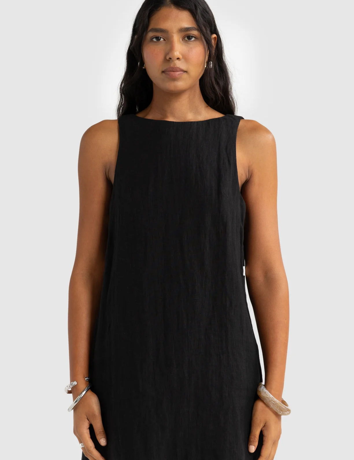 Woman wearing a black sleeveless dress against a white background