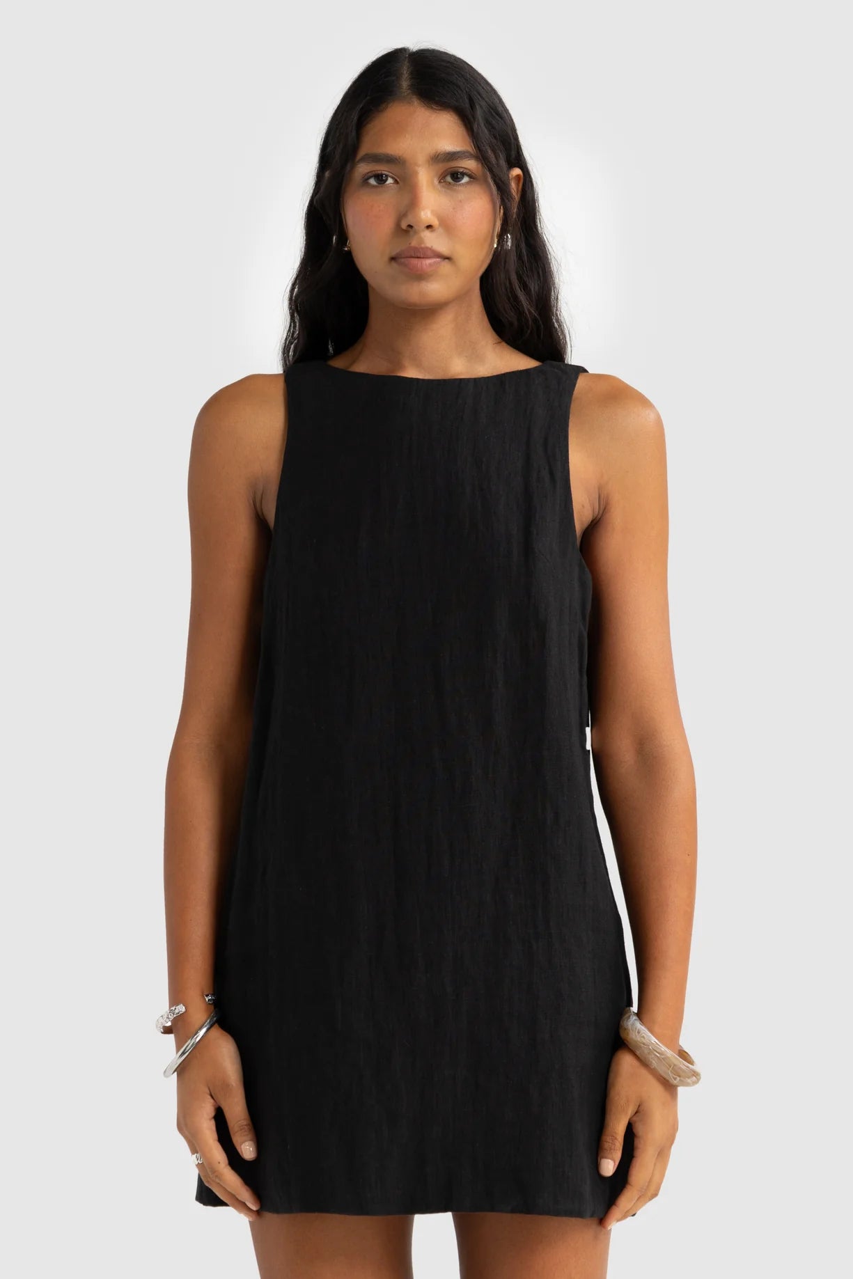 Woman wearing a black sleeveless dress against a white background