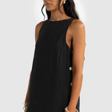 Woman wearing a black sleeveless dress with buttons on a white background