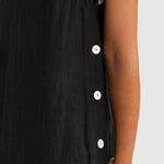 Black sleeveless dress with white buttons on a plain background