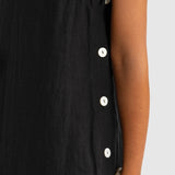 Black sleeveless dress with white buttons on a plain background