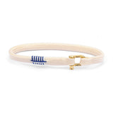 Beige bracelet with a blue and white arrow charm on a white background