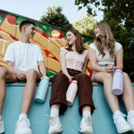 Three friends sitting on a ledge with colorful graffiti in the background
