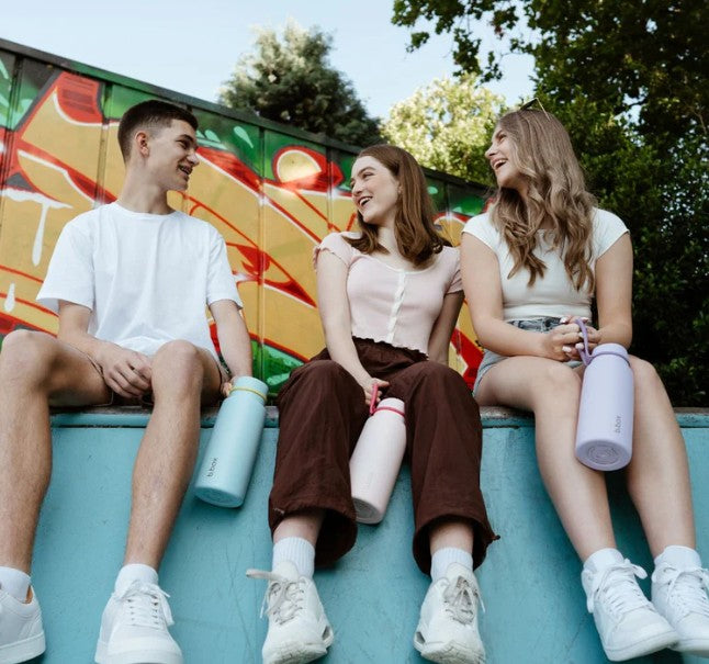 Three friends sitting on a ledge with colorful graffiti in the background