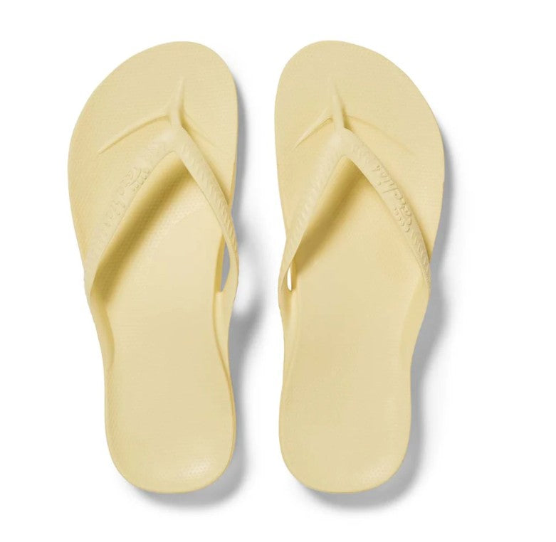 Pair of light yellow flip-flops on a white background