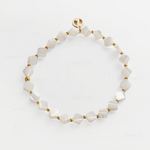 A delicate beaded bracelet made of irregular white mother-of-pearl beads separated by small gold spacer beads, with a gold clasp featuring a circular logo, displayed on a clean white background.