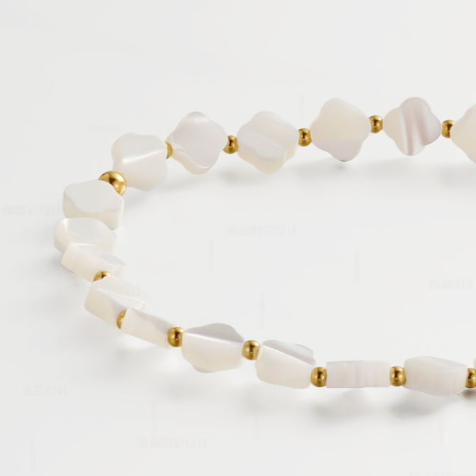 A close-up of a beaded necklace featuring irregular white mother-of-pearl shell beads separated by small gold spacer beads, arranged on a clean white background.