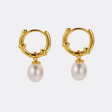 Gold hoop earrings with pearl drops on a white background