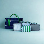 Set of bags including a navy blue tote, gray pouch, and green striped pouches on a light blue background