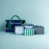 Set of bags including a navy blue tote, gray pouch, and green striped pouches on a light blue background
