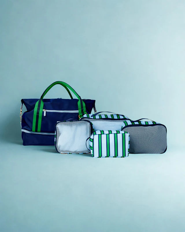 Set of bags including a navy blue tote, gray pouch, and green striped pouches on a light blue background