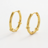 Gold hoop earrings on a light gray background