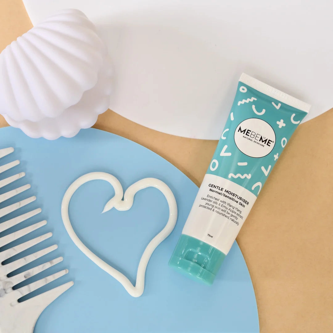A tube of MESE ME Gentle Moisturizer Hand cream placed on a light blue circular prop, surrounded by a white seashell, a white heart-shaped cutout, and a white comb on a beige background.